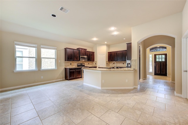 22526 Forbes Field Trl, Spring, TX 77389 - kitchen featuring dark brown cabinets, a sink, stainless steel appliances, arched walkways, and decorative backsplash