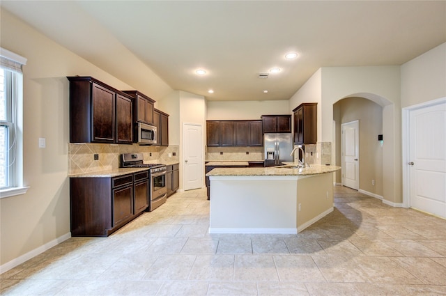 22526 Forbes Field Trl, Spring, TX 77389 - kitchen with light stone counters, dark brown cabinetry, arched walkways, tasteful backsplash, and appliances with stainless steel finishes