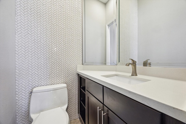 half bathroom with vanity, toilet, and tile walls