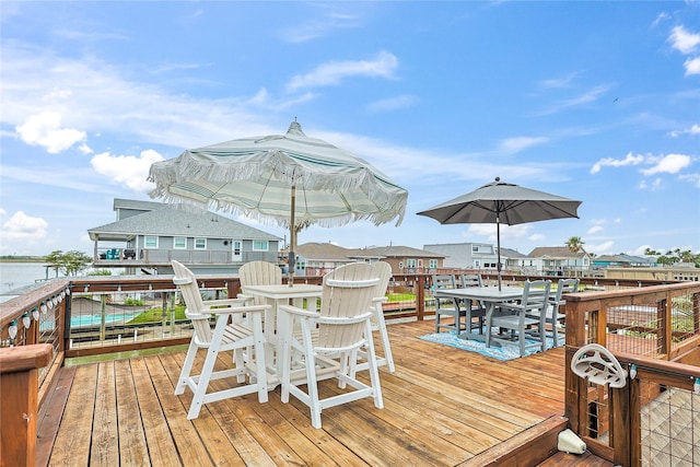 deck featuring outdoor dining area, a water view, and a residential view