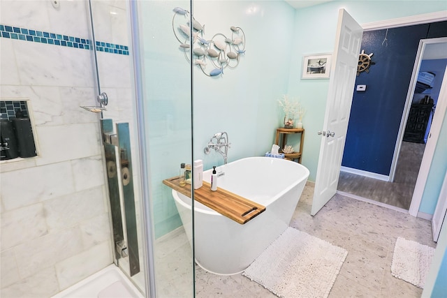 bathroom featuring a freestanding bath, baseboards, and a stall shower