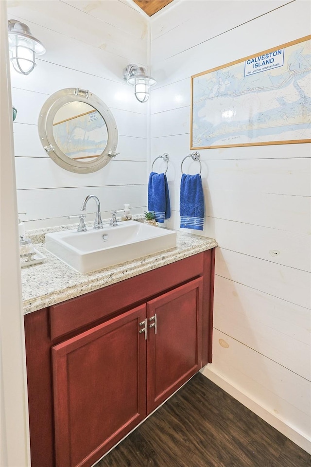 bathroom featuring vanity, wood walls, and wood finished floors