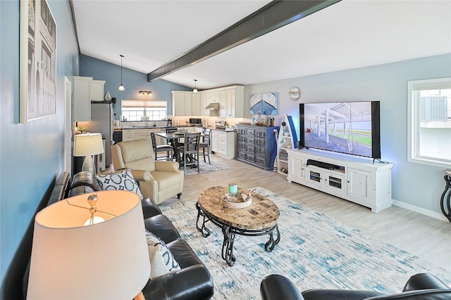 living area with light wood finished floors, lofted ceiling with beams, and baseboards