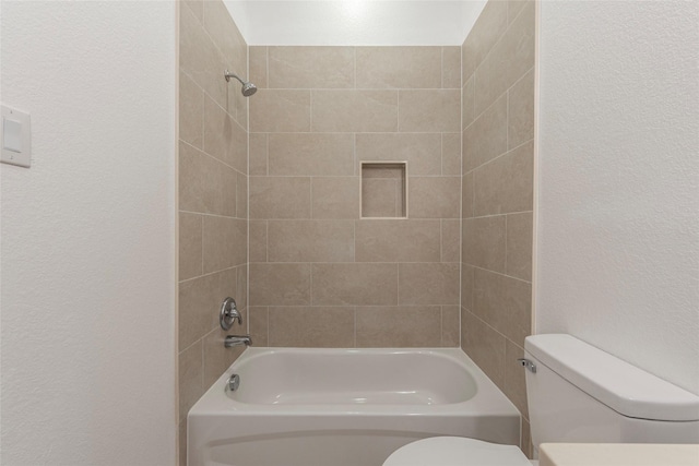 full bath with a textured wall, toilet, and shower / bathtub combination