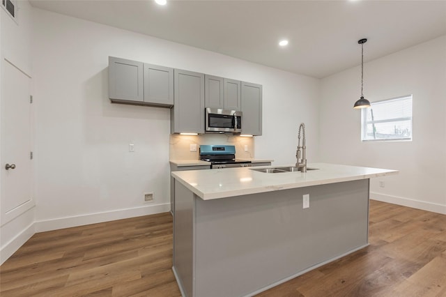 kitchen featuring light wood-style floors, stainless steel appliances, a sink, and gray cabinets