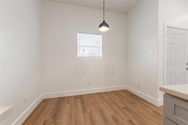 unfurnished dining area with baseboards and light wood-style flooring