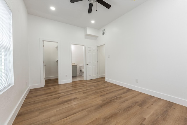 unfurnished bedroom with light wood-style flooring, baseboards, visible vents, connected bathroom, and a spacious closet