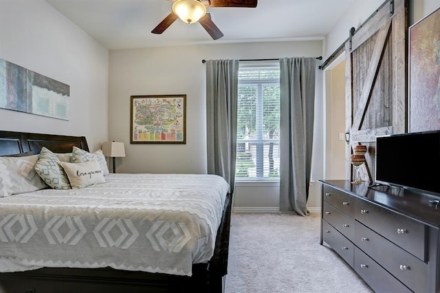 bedroom featuring light carpet, multiple windows, a barn door, and baseboards