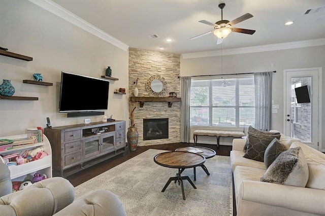 living room featuring ceiling fan, wood finished floors, ornamental molding, a stone fireplace, and recessed lighting