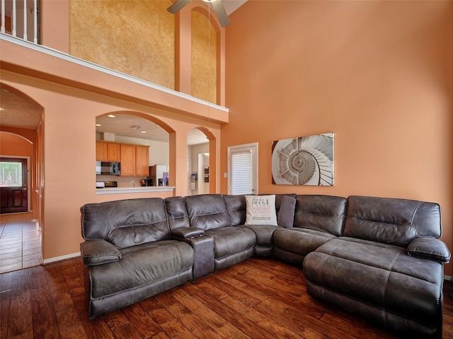23623 Breckenridge Forest Dr, Spring, TX 77373 - living room featuring dark wood finished floors, arched walkways, a ceiling fan, a high ceiling, and baseboards