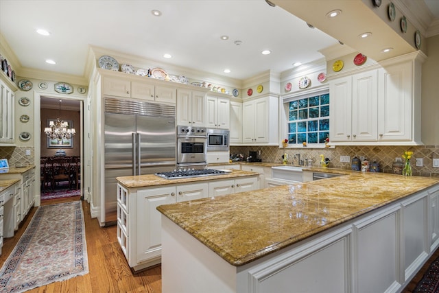 8722 Stable Crest Blvd, Houston, TX 77024 - kitchen with built in appliances, crown molding, a chandelier, a center island, and light stone countertops