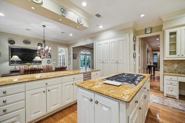 8722 Stable Crest Blvd, Houston, TX 77024 - kitchen with stainless steel gas stovetop, light wood-type flooring, tasteful backsplash, light stone countertops, and glass insert cabinets