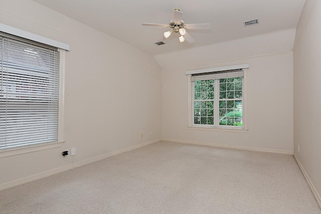 spare room featuring baseboards, visible vents, ceiling fan, vaulted ceiling, and light carpet