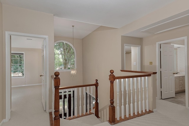 hallway with carpet, attic access, an upstairs landing, and baseboards