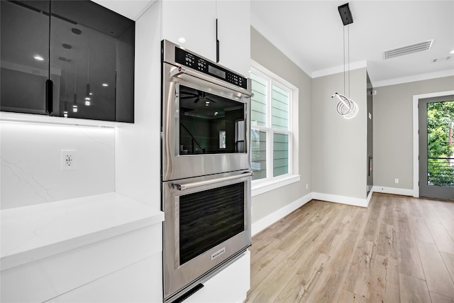 604 W 28th St Unit A, Houston, TX 77008 - kitchen with stainless steel double oven, crown molding, light wood finished floors, white cabinetry, and light countertops