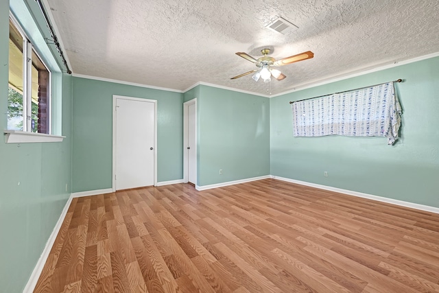 empty room featuring a ceiling fan, wood finished floors, baseboards, a textured ceiling, and ornamental molding