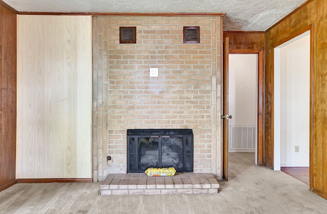 unfurnished living room featuring wooden walls, carpet, baseboards, ornamental molding, and a brick fireplace