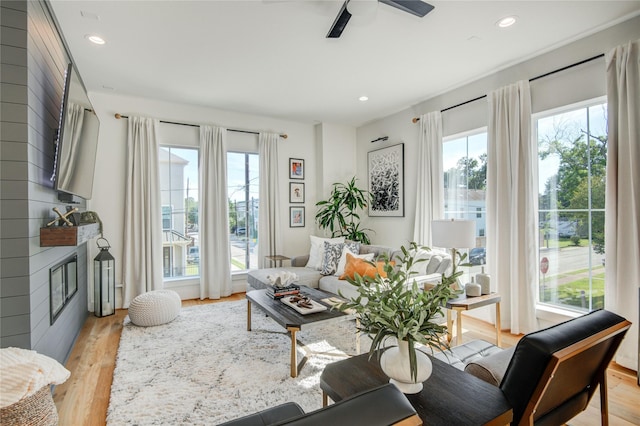 living area featuring light wood finished floors, a fireplace, ceiling fan, and recessed lighting