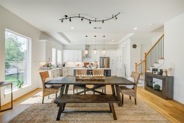 dining space featuring light wood-type flooring, stairway, a tray ceiling, and recessed lighting