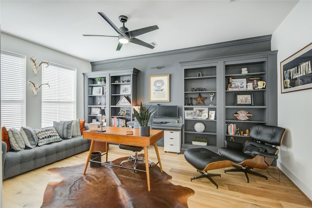 office area featuring a ceiling fan, light wood finished floors, and built in shelves