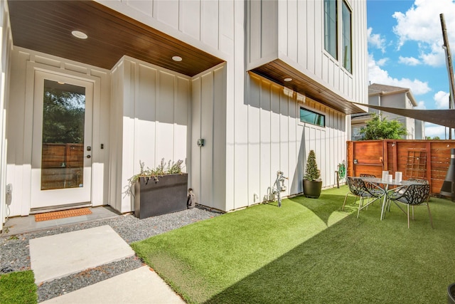 property entrance with board and batten siding and a lawn
