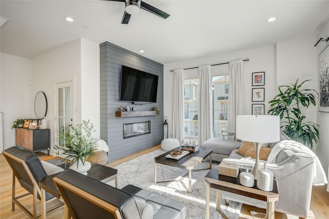 living room with wood finished floors, ceiling fan, a fireplace, and recessed lighting