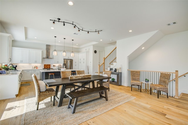 dining space featuring a raised ceiling, stairway, light wood-style floors, recessed lighting, and baseboards
