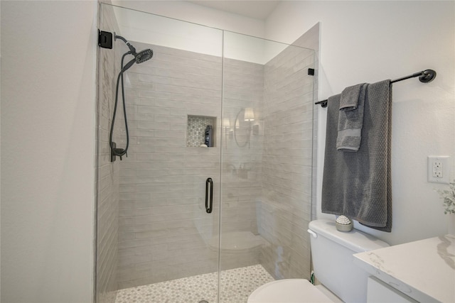 bathroom with toilet, a shower stall, and vanity