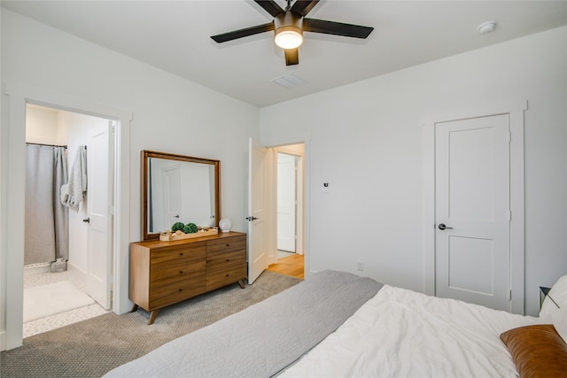 bedroom with light colored carpet, ceiling fan, and connected bathroom
