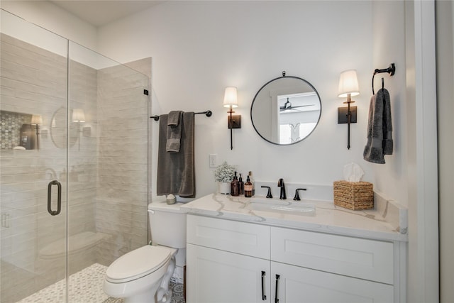 bathroom with vanity, toilet, a shower stall, and a ceiling fan