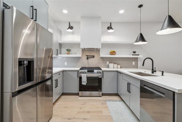 kitchen featuring a sink, open shelves, light wood-type flooring, gray cabinetry, and appliances with stainless steel finishes