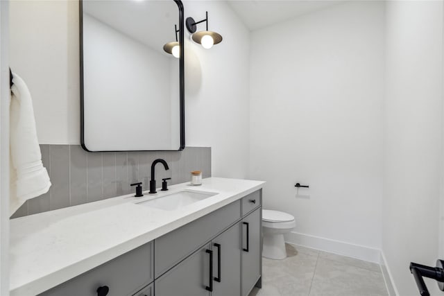 bathroom featuring baseboards, vanity, toilet, and decorative backsplash