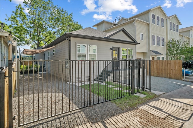 view of front facade featuring a fenced front yard, a shingled roof, and a gate