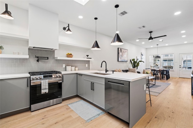 kitchen featuring a ceiling fan, a sink, open shelves, stainless steel appliances, and gray cabinets