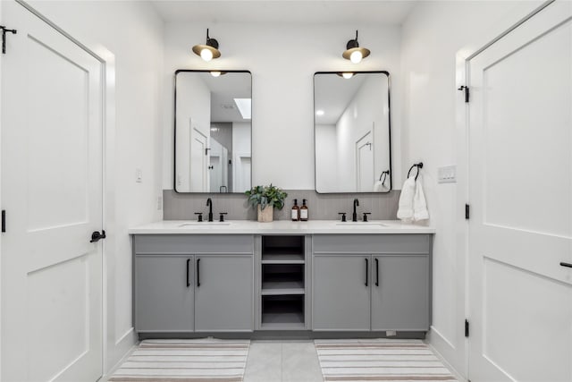 bathroom with double vanity, tasteful backsplash, baseboards, and a sink