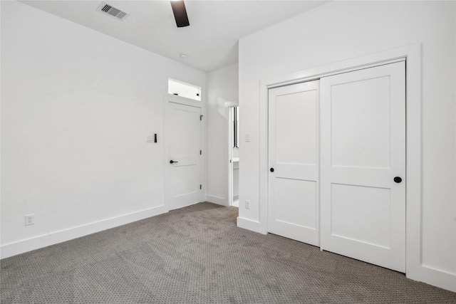 unfurnished bedroom with carpet, a closet, visible vents, baseboards, and ceiling fan