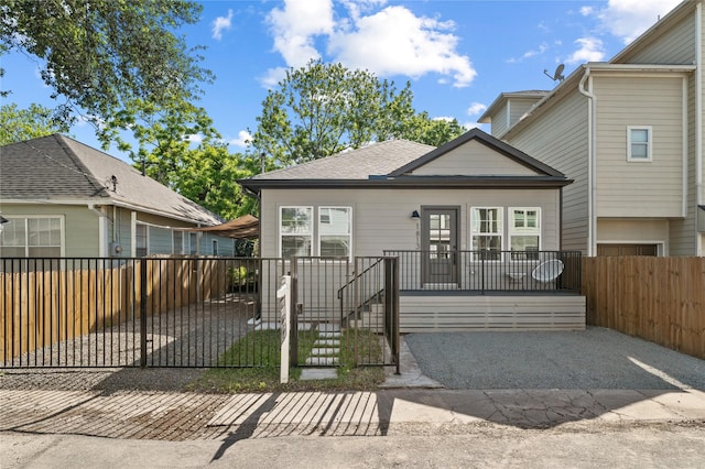 view of front of property featuring a fenced front yard and a shingled roof