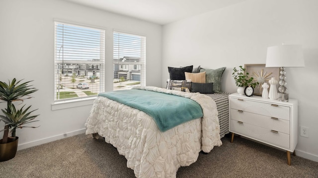 bedroom with dark colored carpet and baseboards