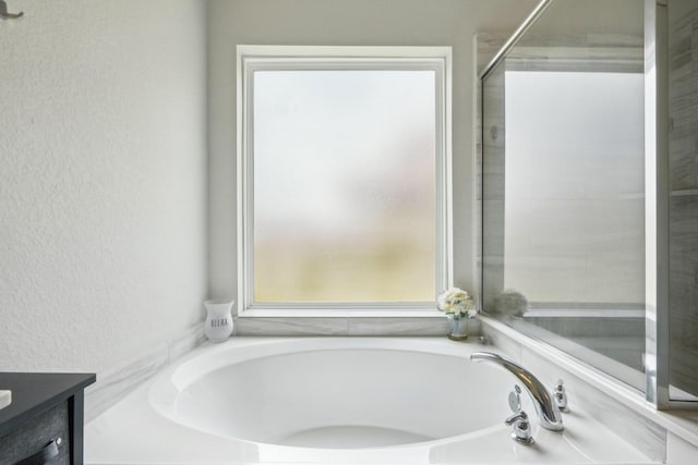 full bathroom featuring vanity, a textured wall, a garden tub, and an enclosed shower