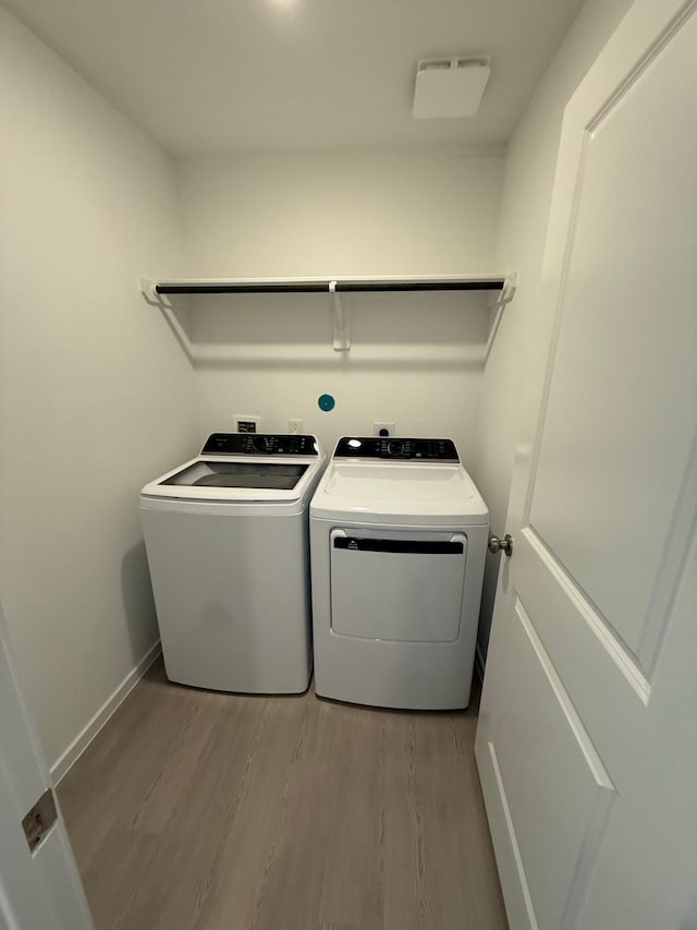 laundry room with laundry area, baseboards, independent washer and dryer, and wood finished floors