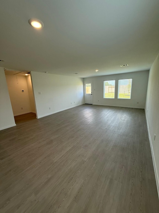 unfurnished room featuring wood finished floors, visible vents, and baseboards