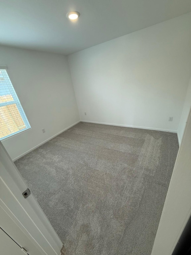 carpeted empty room featuring baseboards