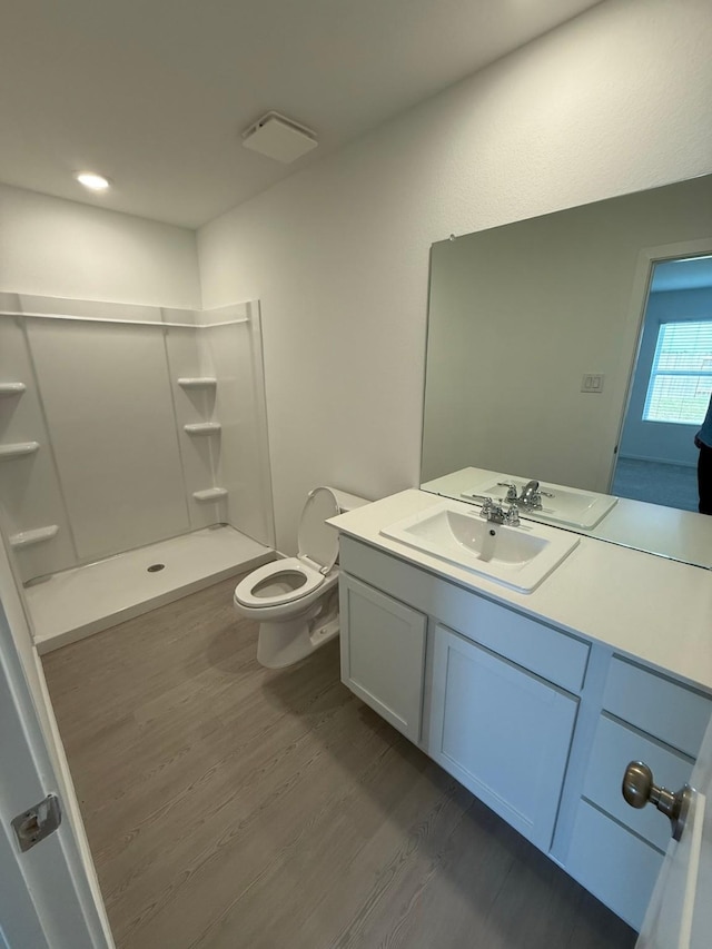 bathroom with a stall shower, vanity, toilet, and wood finished floors