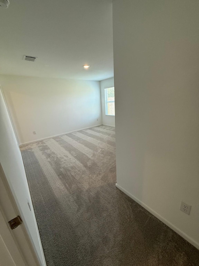 empty room featuring baseboards, visible vents, and carpet