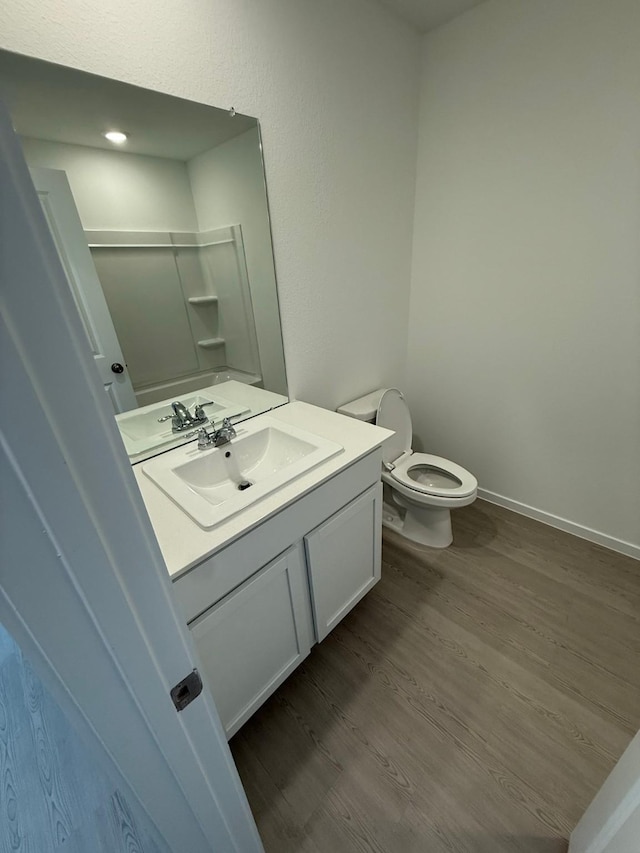 bathroom with toilet, baseboards, wood finished floors, and vanity