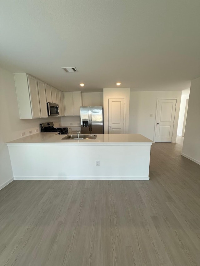 kitchen featuring visible vents, a sink, wood finished floors, light countertops, and appliances with stainless steel finishes