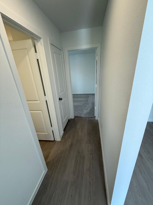 hall featuring dark wood-style flooring and baseboards