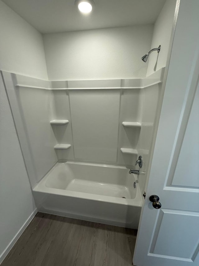 full bath featuring baseboards, wood finished floors, and bathtub / shower combination