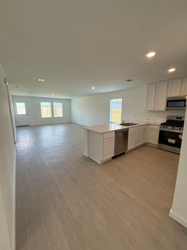 kitchen with stainless steel appliances, open floor plan, light wood-style flooring, and recessed lighting