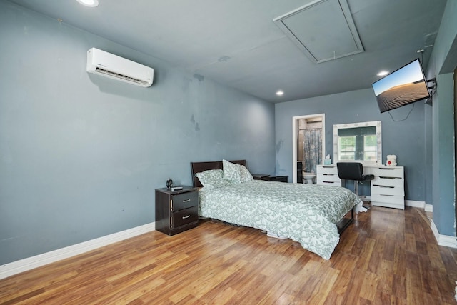bedroom featuring wood finished floors, attic access, recessed lighting, a wall unit AC, and baseboards